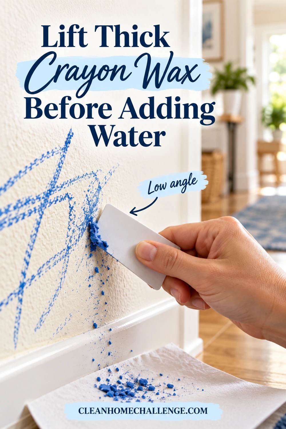 A plastic card held at a low angle gently lifts a raised blue crayon wax ridge from a painted wall.