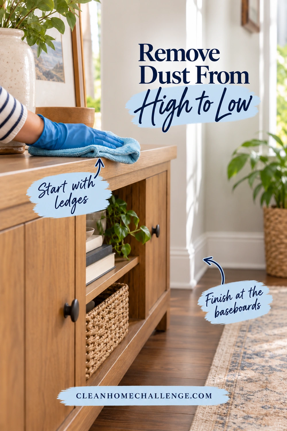 A blue-gloved hand wipes the top of a wooden sideboard with a folded cloth, with the lower shelves and a wall baseboard visible.
