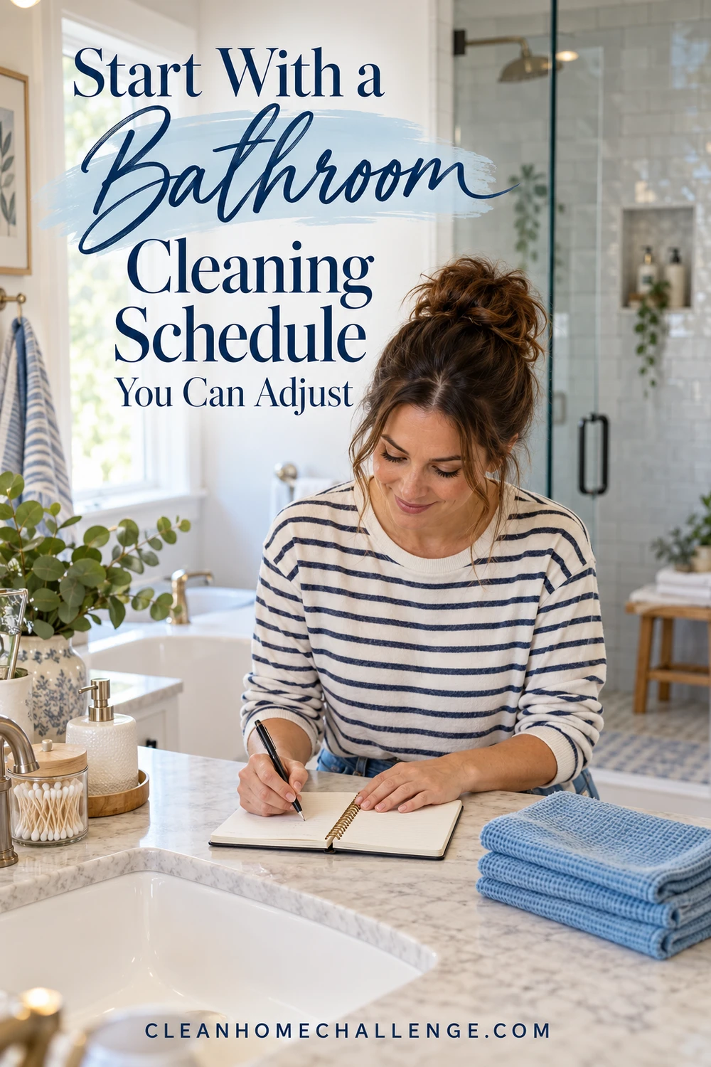 Woman in a navy-striped shirt writing in a notebook at a bathroom counter beside folded blue cloths.