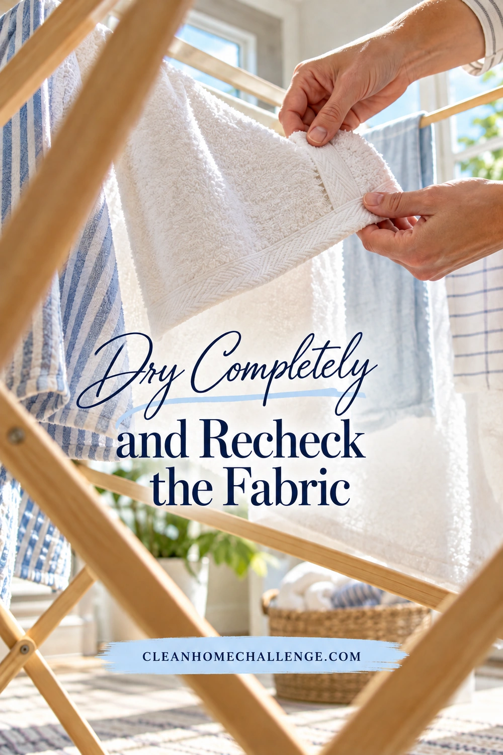 Hands check the thick hem of a clean white towel hanging on a wooden drying rack in a bright laundry space.