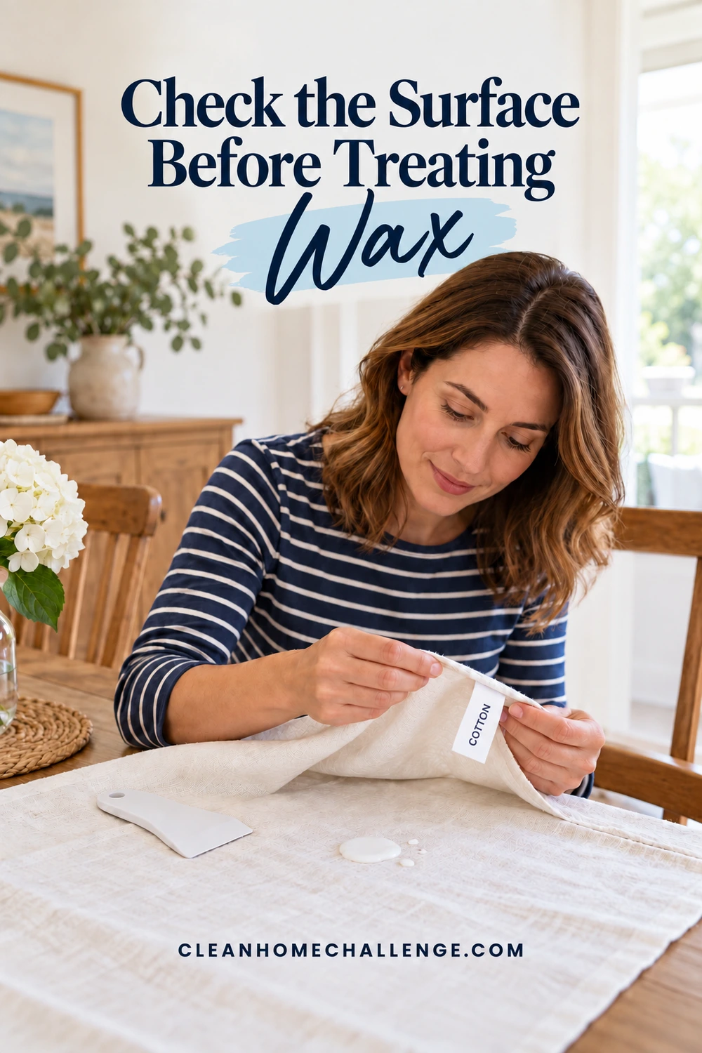 Woman in a striped shirt checking a cotton tag on a white tablecloth beside cooled wax and a rounded plastic scraper.