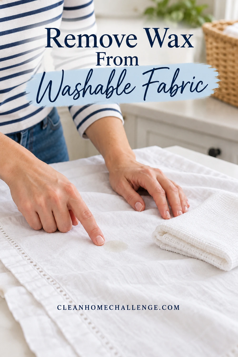 Hands indicating a faint oily mark on a white cotton tablecloth beside folded absorbent cloths on a laundry counter.