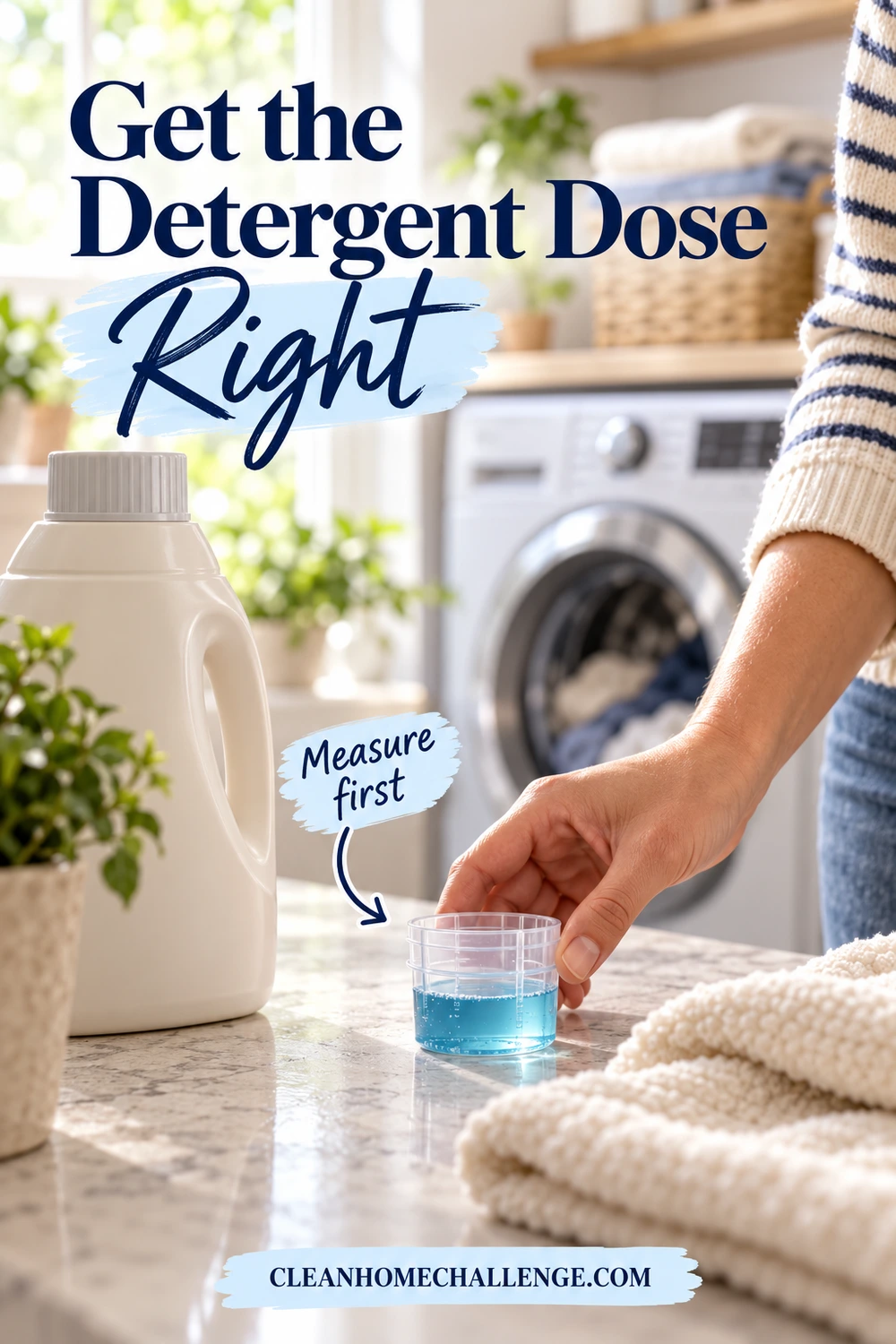 A hand holds a transparent measuring cap containing blue detergent beside a closed bottle and a cream towel on a laundry counter.