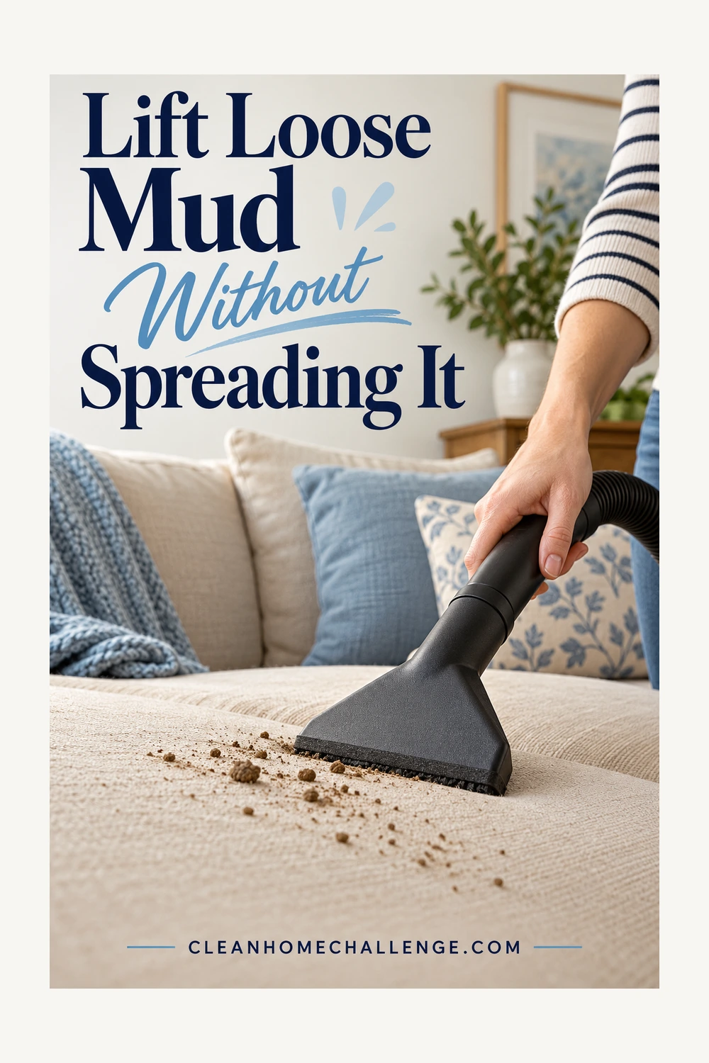 A hand uses a black dry-vacuum upholstery nozzle to remove loose soil from a beige sofa.