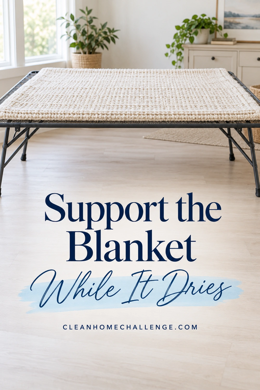 A cream wool blanket lies flat across a broad rectangular mesh drying support in an airy room.